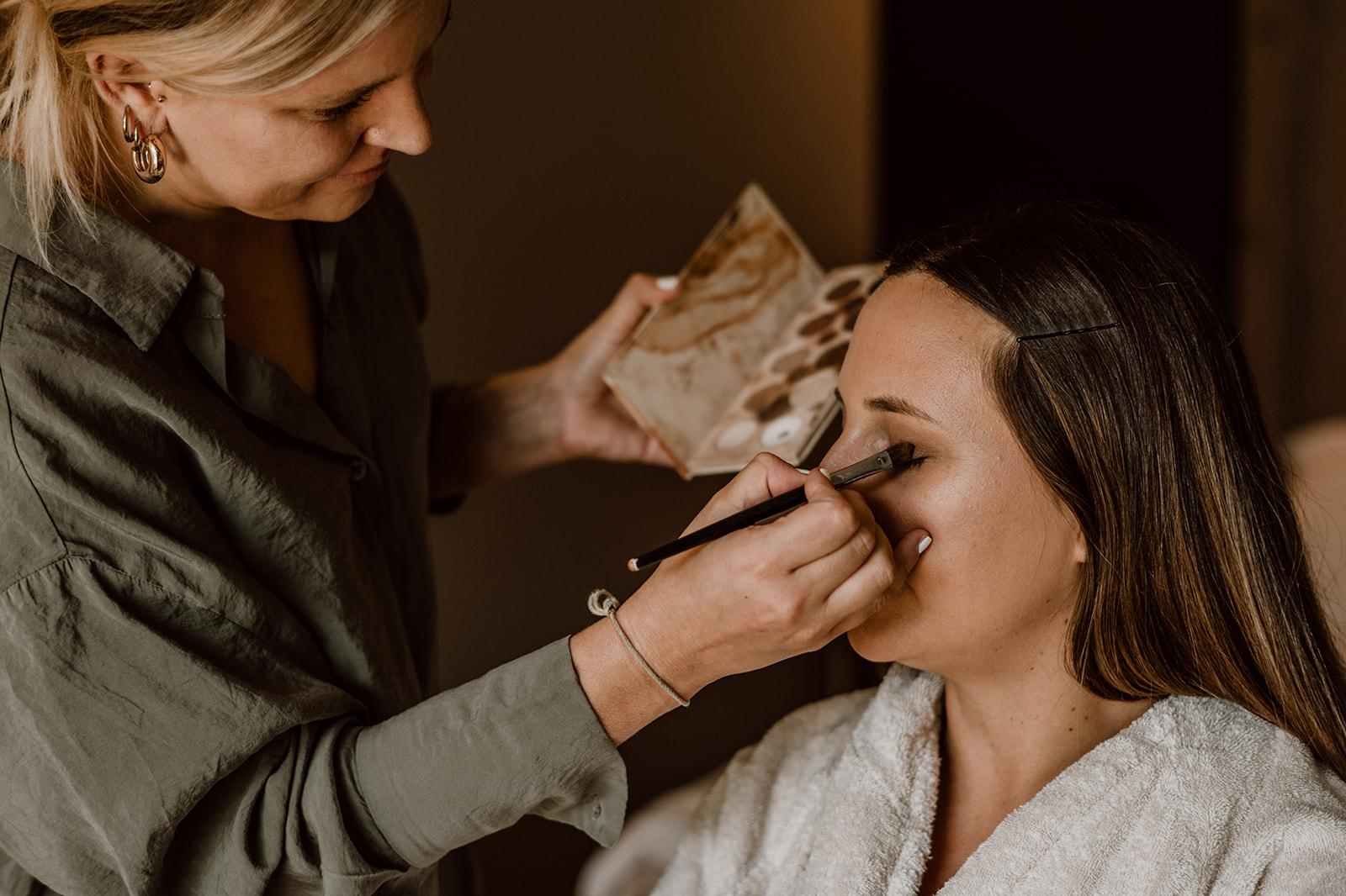 Make-Up-Artistin schminkt Augen der Braut