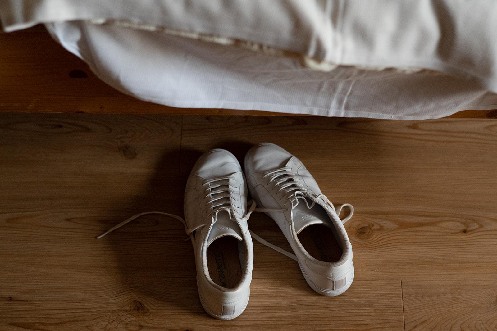 weiße Sneaker stehen vor einem Bett